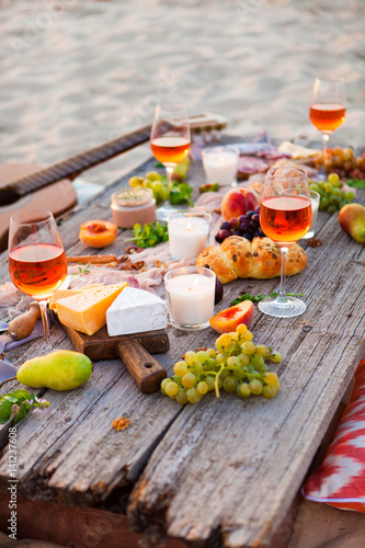 Picnic on the beach at sunset in boho style, food and drink concept