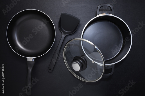 Top view frying pan and pot on black table.