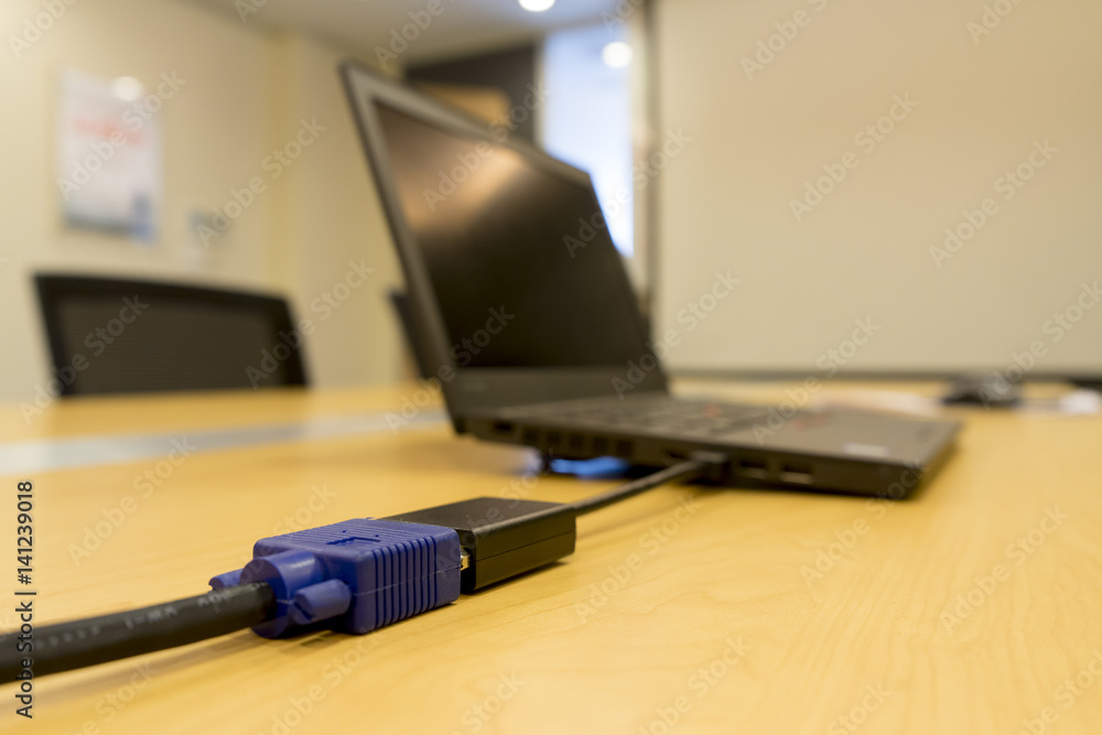 Mini-DVI from laptop to VGA video cable projector on wooden table in meeting room Mini-DVI from laptop to VGA video cable projector on wooden table in meeting room