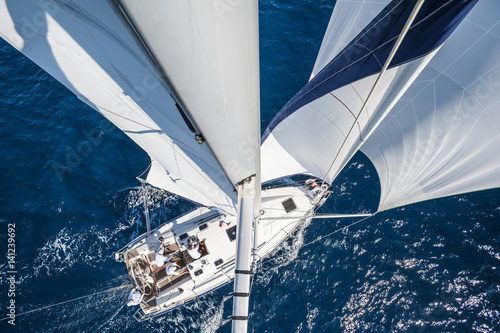 Fotografie Sailing boat with spinnaker from top of the mast, motion blurred sea