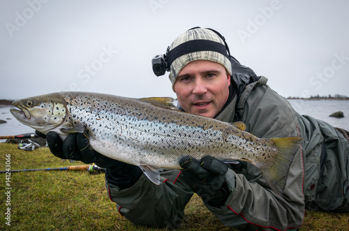 Happy angler with huge sea trout fishing trophy