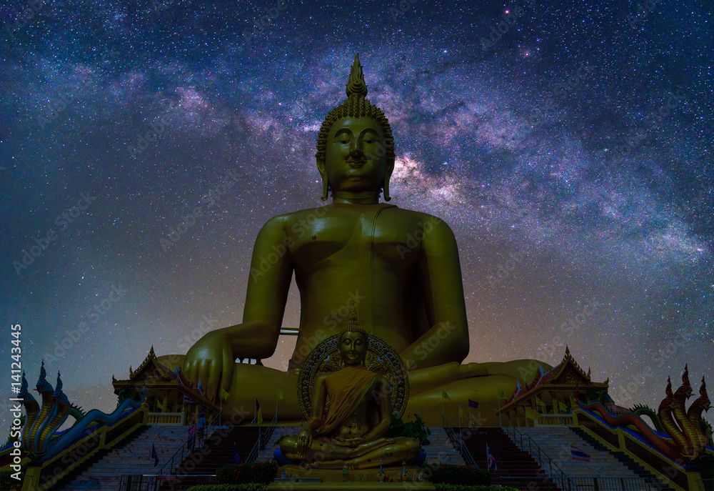 Naklejka premium Landscape with Milky way galaxy. Night sky with stars and silhouette Biggest Buddha statue at temple in Thailand