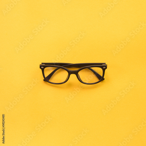 Black modern eye glasses on yellow background. photo