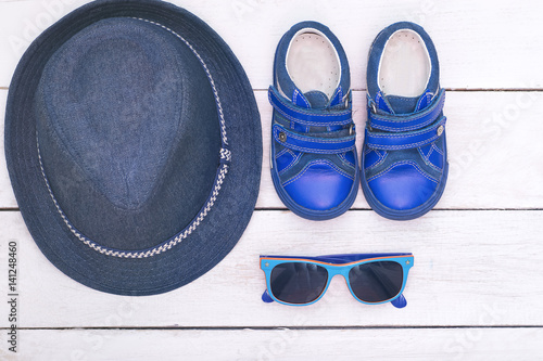 Children's accessories for the summer: sunglasses, hat, boots blue. Flat lay