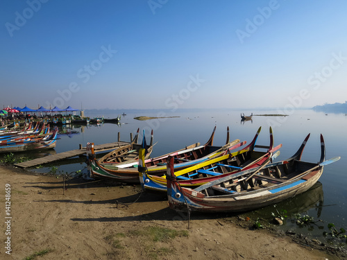 Wallpaper Mural Colorful wooden boats on bank of peaceful still water lake with port, birds and clear blue sky background Torontodigital.ca