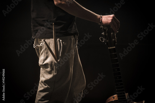 young man with acoustic guitar on black background