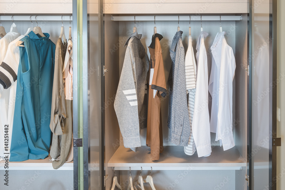clothes hanging on rail in modern wardrobe