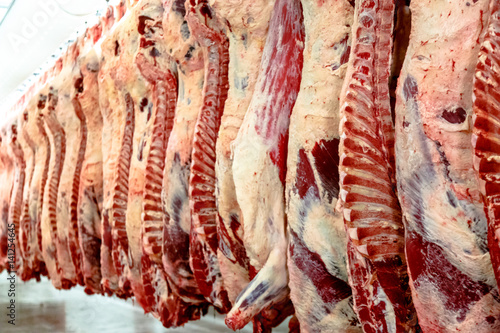 Фотография The meat processing plant. carcasses of beef hang on hooks.