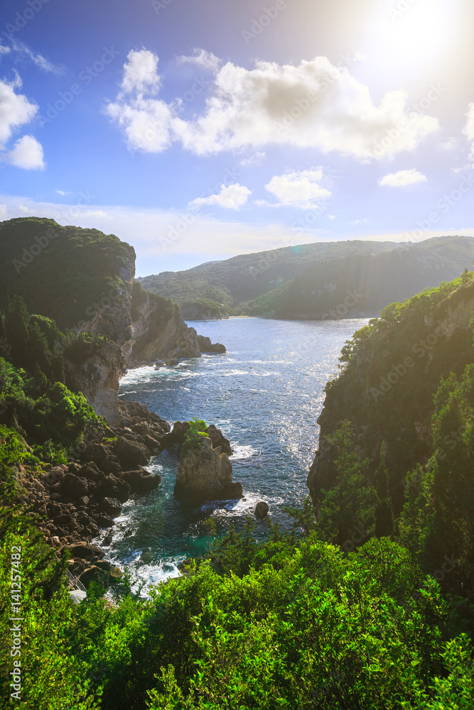 Beautiful summer panoramic seascape. View of the coastline into the sea bays with crystal clear azure water. Lonely rock with a tree on top. A small tree on top. Paleokastrica. Corfu. Greece.