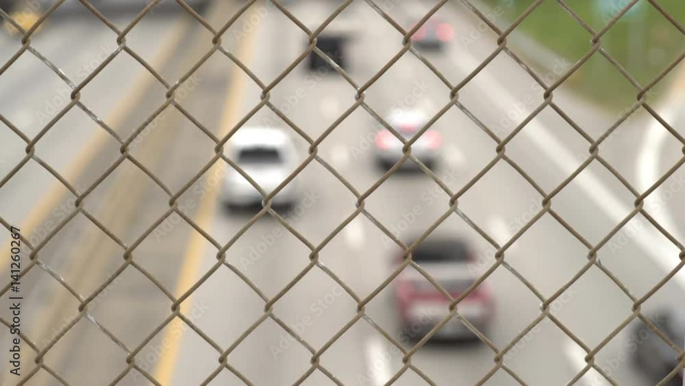 Highway traffic going thru city with focus on fence.
Highway traffic going thru city with focus on fence.