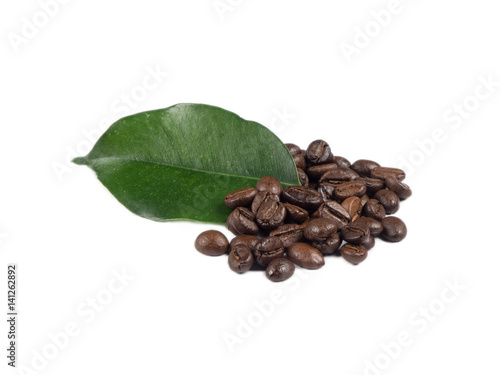 Pile of coffee grains with green leaf over white isolated background.