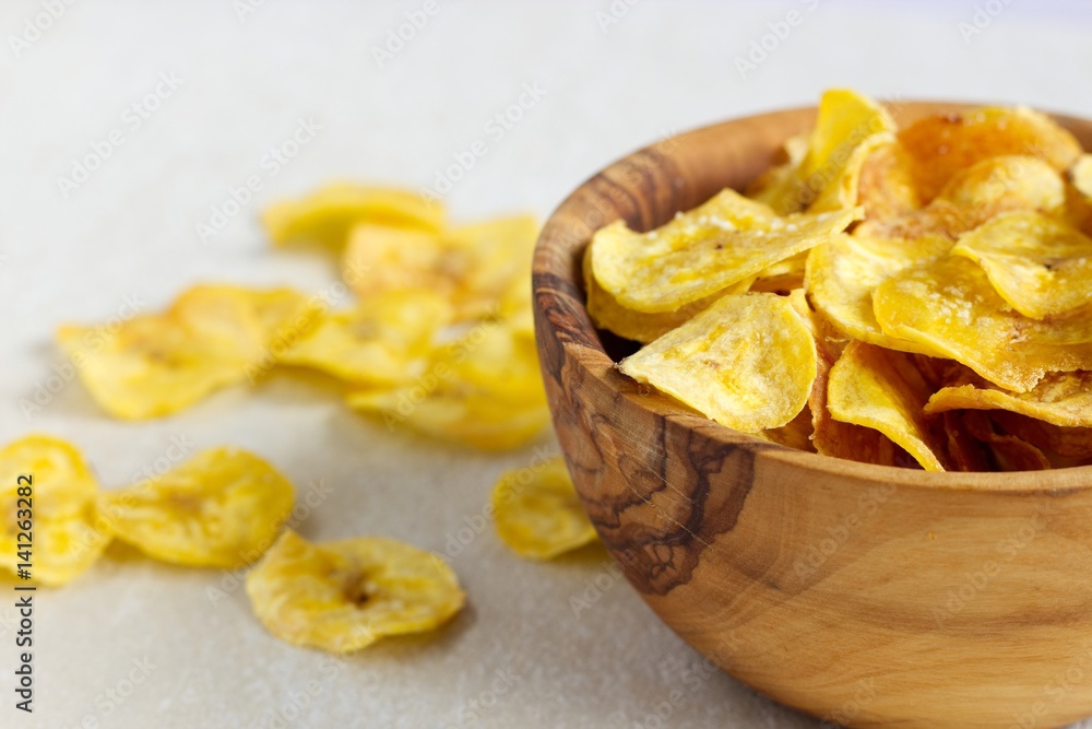 Fried plantain chips in a wooden bowl.