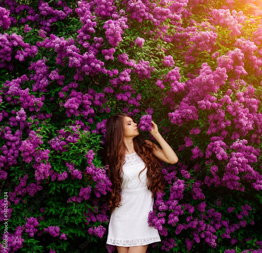Beautiful sexy woman girl on the background of blooming lilacs, happy young woman girl in white dress in the spring Beautiful sexy woman girl on the background of blooming lilacs, happy young woman girl in white dress in the spring