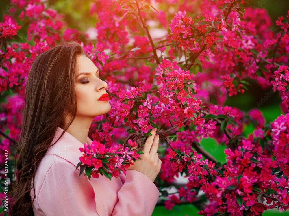 Fototapeta premium a young girl in the spring near flowering trees , a touch of spring , the fragrance of flowers