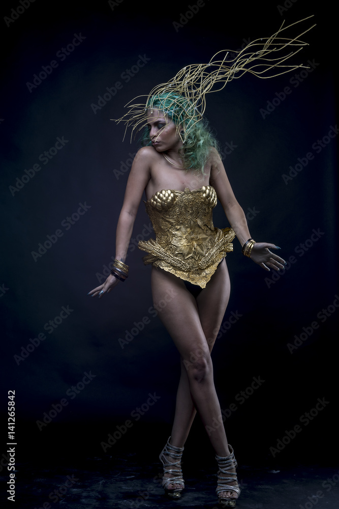 Latin woman with green hair and gold tiara, wears a handmade warrior armor