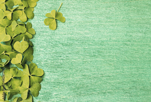 Background for St. Patrick's Day celebration. Green shamrocks clovers on wooden background photo