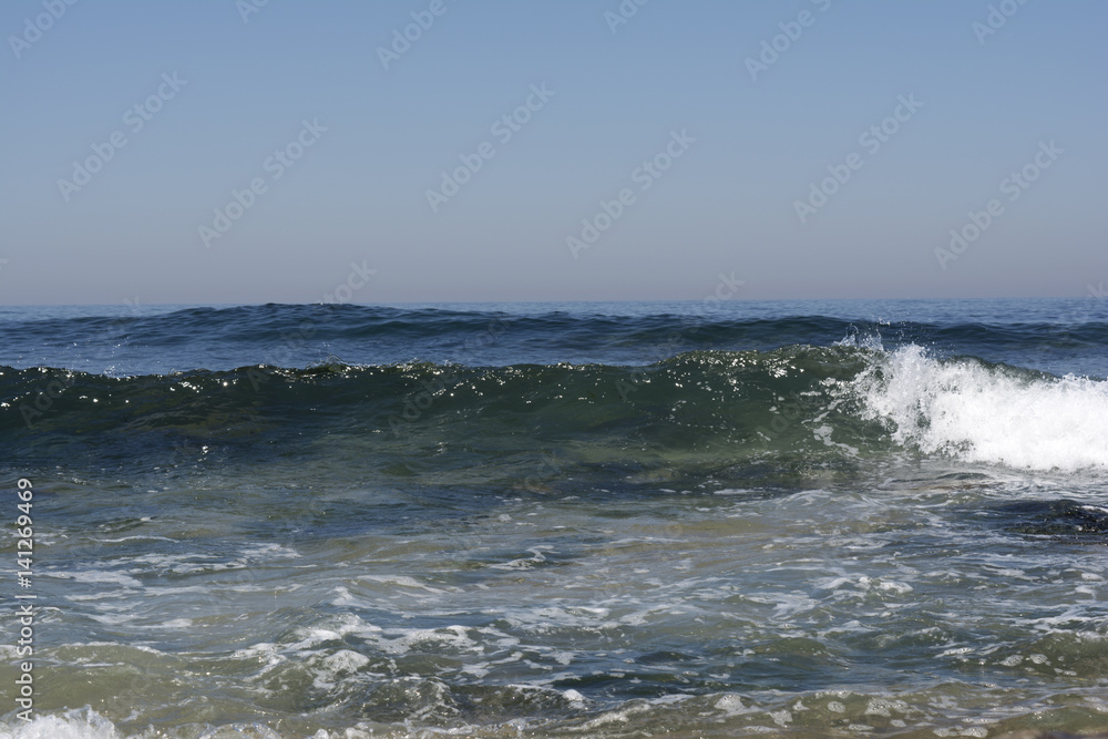 Small waves crashing on the beach on a summer day