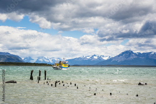 Yellow fishermen boat near old wooden pier in Last hope bay. Puerto Natales, Antarctic Patagonia, Chile photo