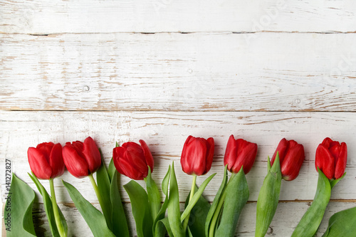 beautiful red tulips on white wooden background. Top view.