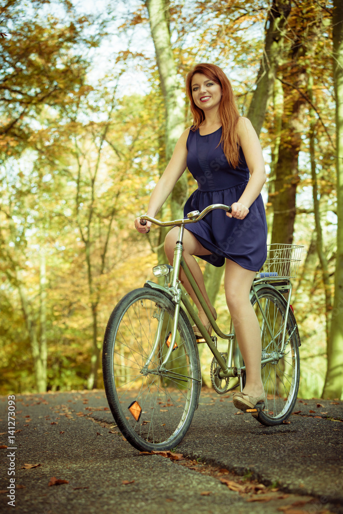 Naklejka premium Redhead lady cycling in park.