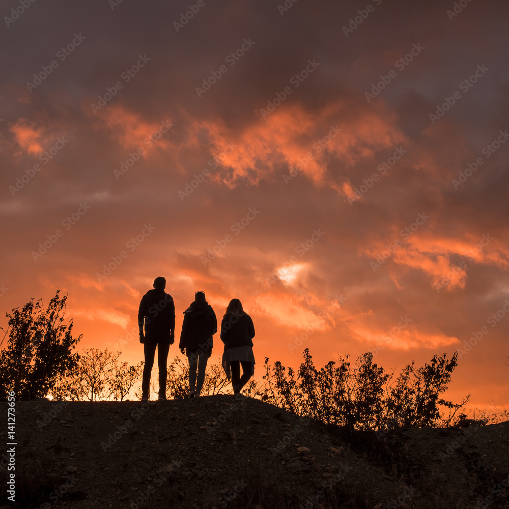 Three silhouettes in dramatic sunset