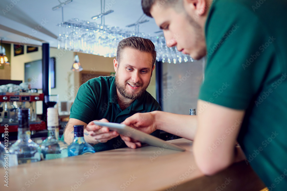 Waiters, bartenders barista rest with the tablet in a break cafe bar restaurant. Waiters, bartenders barista rest with the tablet in a break cafe bar restaurant.
