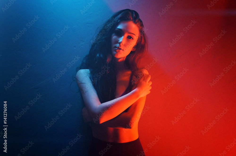 Model in seductive black lingerie with light neon colored spotlights