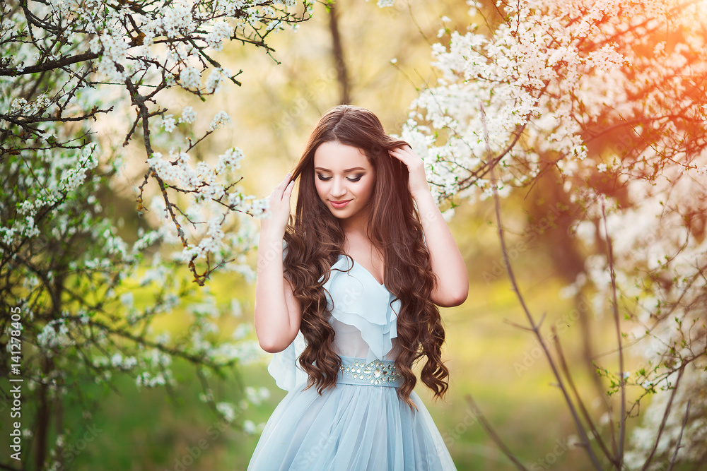Happy beautiful young woman with long black healthy hair enjoy fresh flowers and sun light in blossom park at sunset. Happy beautiful young woman with long black healthy hair enjoy fresh flowers and sun light in blossom park at sunset.