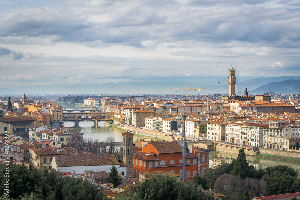 The cloudy sky over Florence. Birds over the river Arno and the Old Bridge
