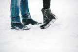 legs embracing couples standing on the snow