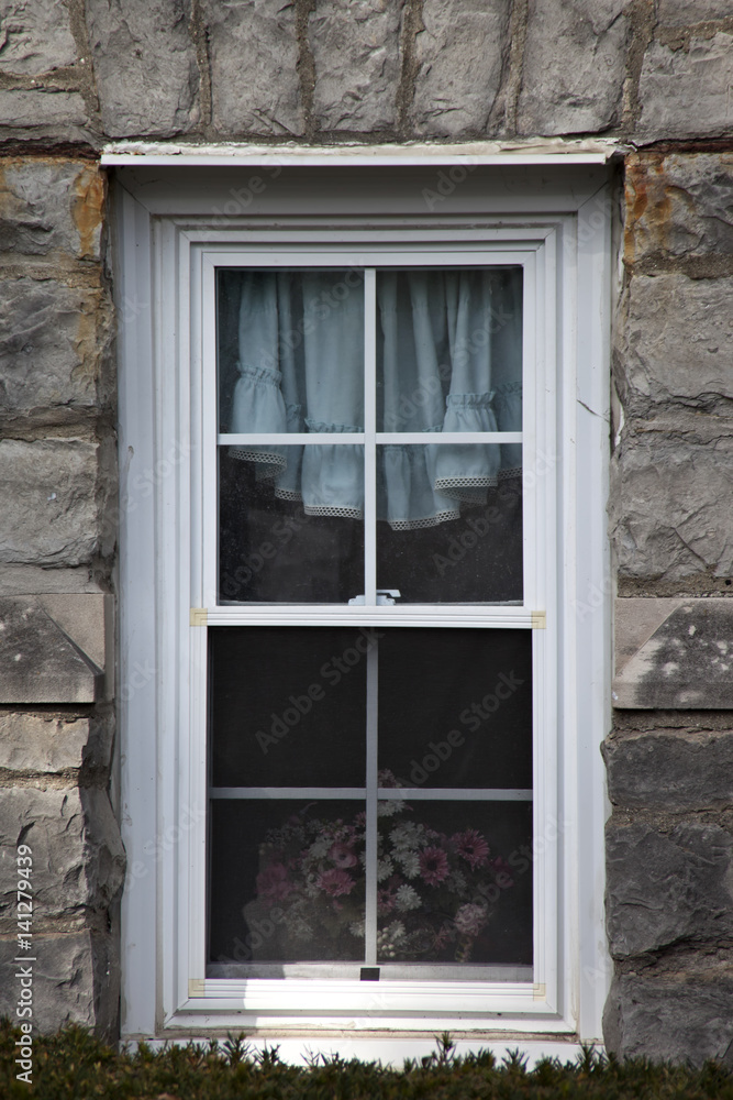 Fototapeta premium Basket of colorful flowers sitting on windowpane, surrouned by beautiful, rustic stonework.