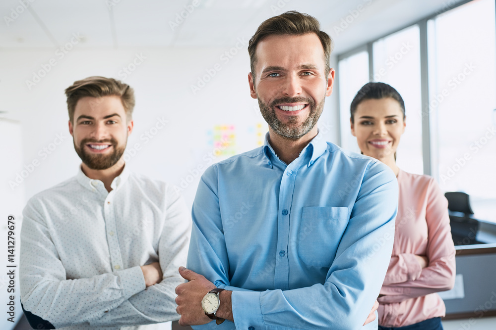 Group of happy, motivated business people standing together at office with their leader Group of happy, motivated business people standing together at office with their leader