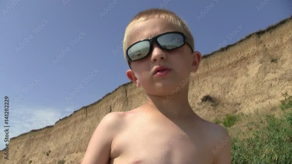 a boy in sunglasses at sea/cheerful boy in black sunglasses on vacation a boy in sunglasses at sea/cheerful boy in black sunglasses on vacation