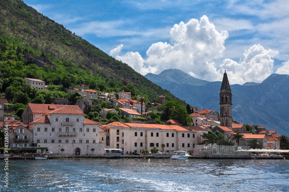 View from boat at Perast cityscape with bank, ancient houses, fort tower and church. The Adriatic sea, Kotor gulf, Montenegro