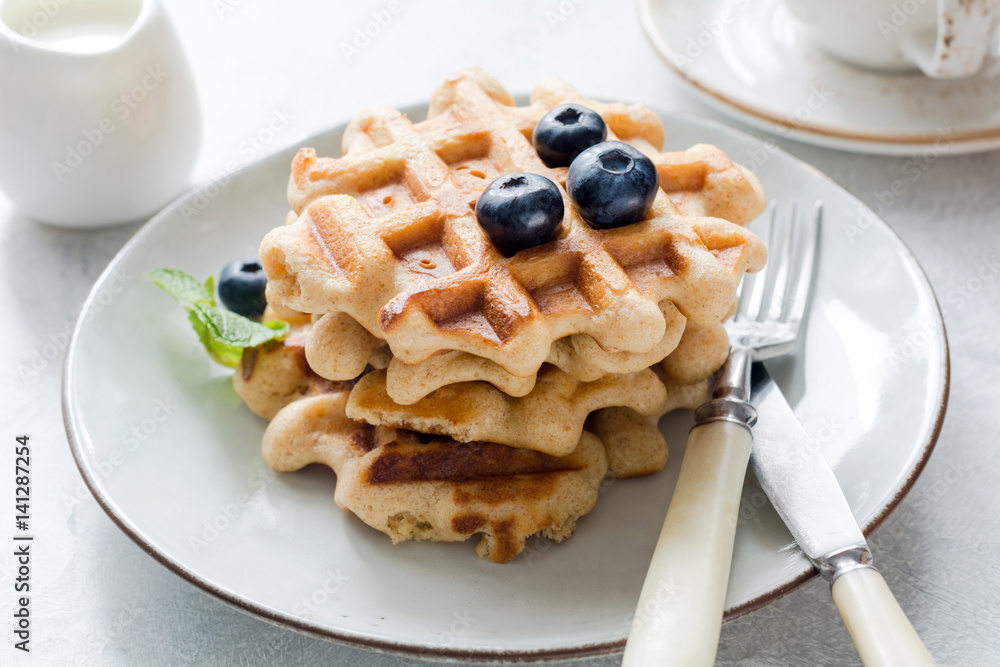 Belgian waffles with blueberries and honey on a plate, closeup view