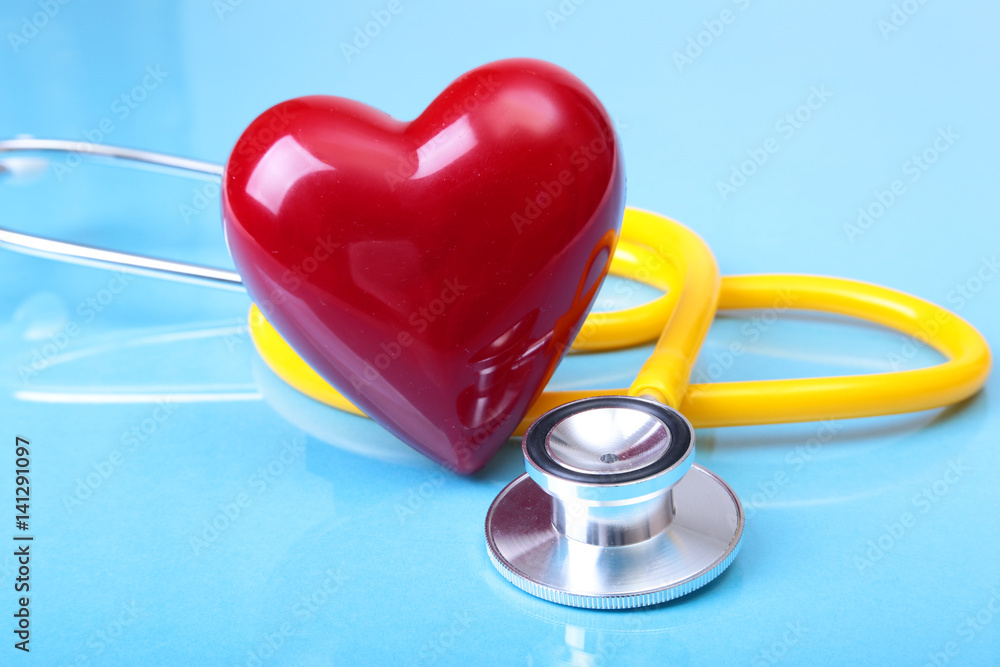 Medical stethoscope and red heart isolated on blue mirror background Medical stethoscope and red heart isolated on blue mirror background