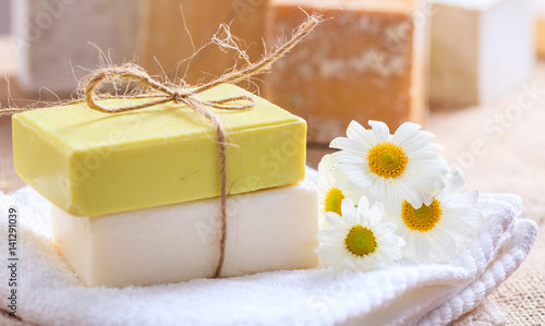 Handmade soap bars and chamomile on wooden background