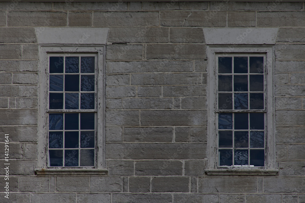 Two blue stained textured retangular windows on gray concrete block wall.