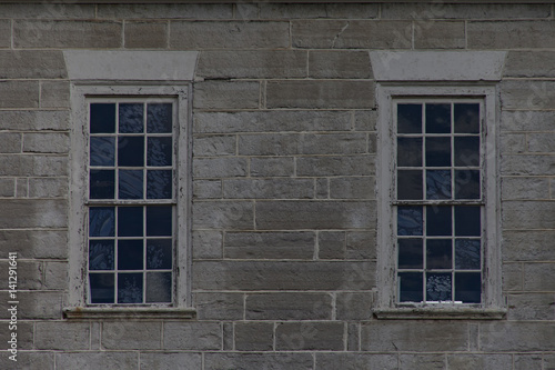 Two blue stained textured retangular windows on gray concrete block wall.