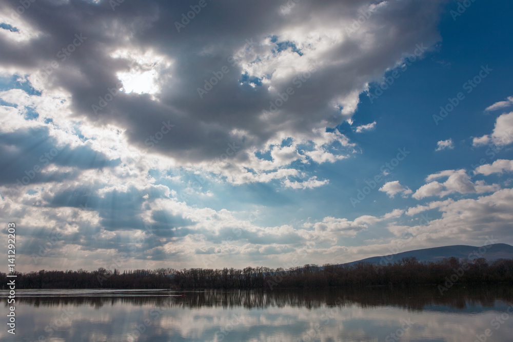 Obraz premium Tranquil scenery of a river with nice cloudscape and sunbeams