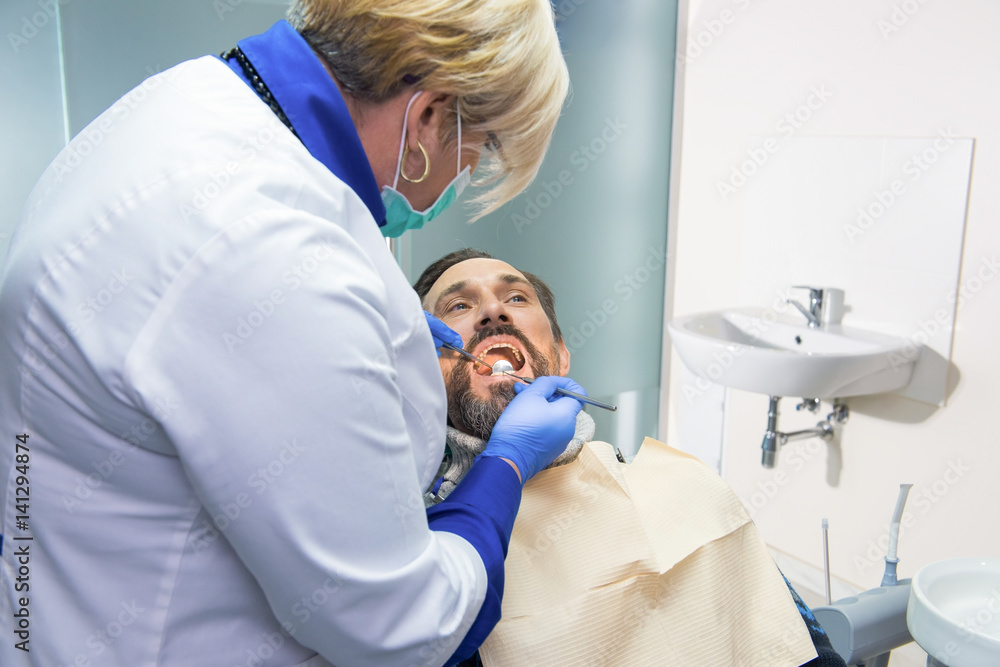Obraz premium Female dentist at work. Doctor checking teeth of patient.