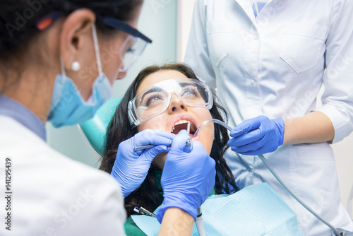 Young woman and dentists. Lady in protective glasses.