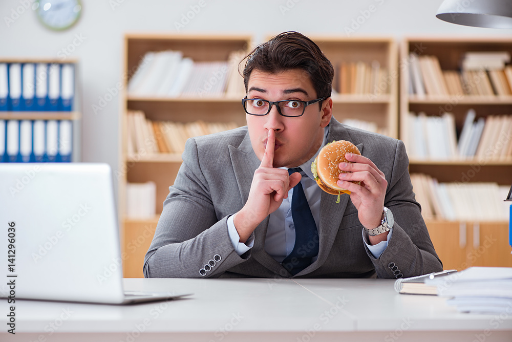 Fototapeta premium Hungry funny businessman eating junk food sandwich
