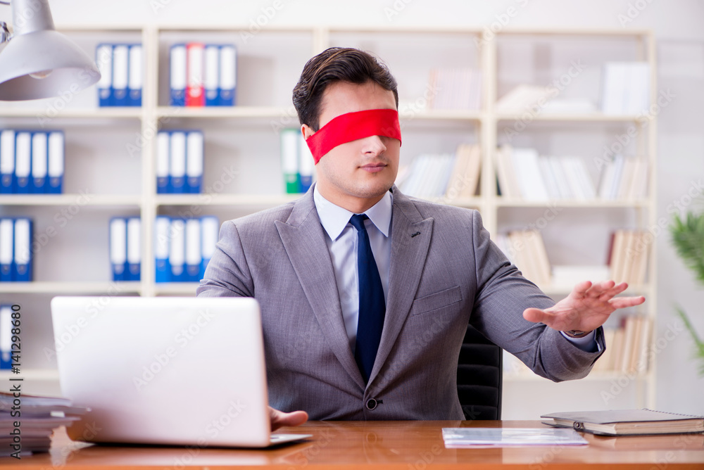 Obraz premium Blindfold businessman sitting at desk in office