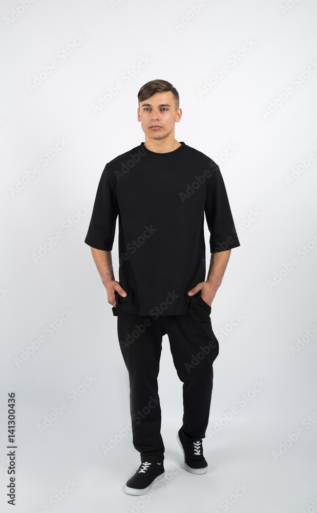 Young muscular man wearing black clothes and sneakers on white background Young muscular man wearing black clothes and sneakers on white background