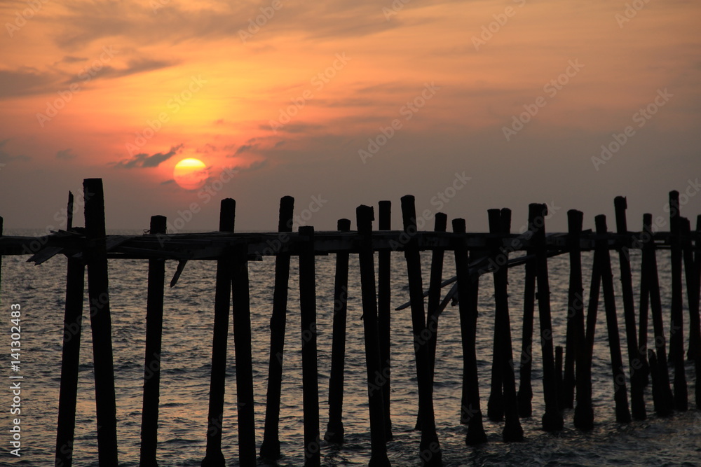 Sunset over the sea and wood bridge 