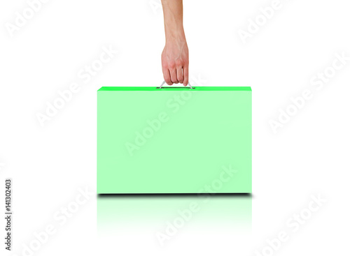 Hand holds a green box with a handle. Packing box for laptop. Stands on a reflection floor. Isolated on white background