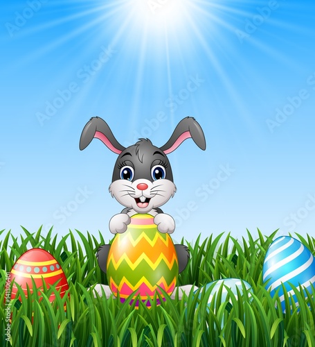 Cartoon bunny holding easter eggs in the grass