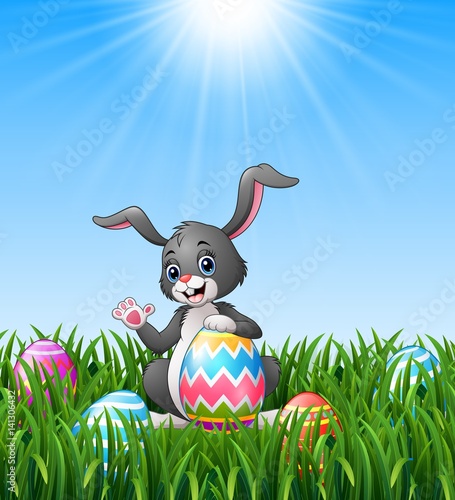 Cartoon bunny waving hand with holding easter egg in the grass