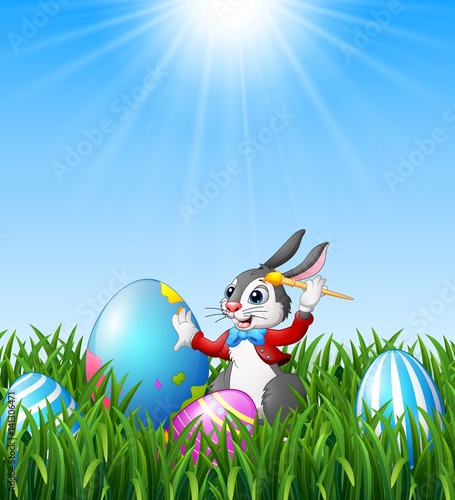 Cartoon easter bunny painting easter eggs in the grass